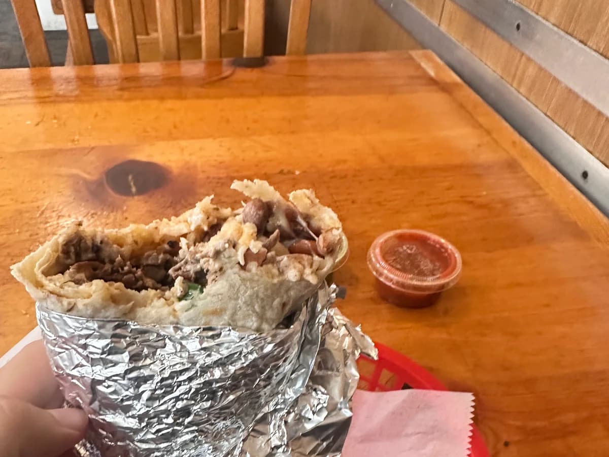 A Mission-style burrito, partially unwrapped on its foil